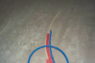 Yeni bir apartman dairesinde elektrik kabloları ve ısıtma boruları döşenmiş radyatör.