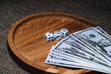 Tahta bir plaka oyununda üç zar bir yığın paranın üzerinde yatıyor.