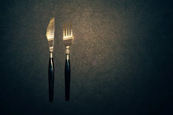 Μαχαίρι Και Πιρούνι Μαύρα Μαγειρικά Σκεύη Τοποθετημένα Μαύρο Τραπέζι Πάνω — Φωτογραφία Αρχείου