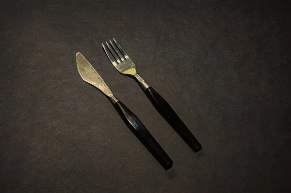 Μαχαίρι Και Πιρούνι Μαύρα Μαγειρικά Σκεύη Τοποθετημένα Μαύρο Τραπέζι Πάνω — Φωτογραφία Αρχείου