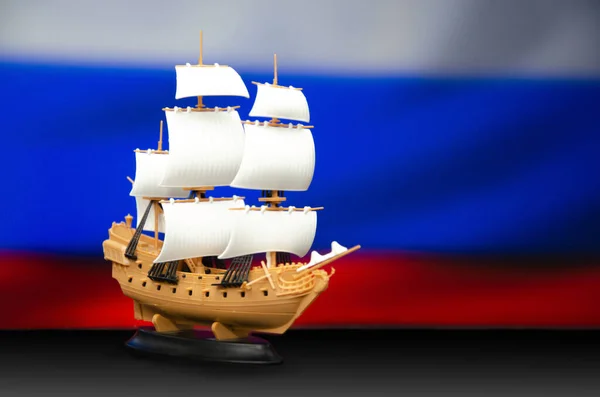 A childrens toy ship on the background of the flag of the Russian Federation. — Photo