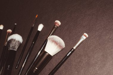 Siyah arkaplanda makyaj fırçaları, metin ve güzellik eklemek için bir yer