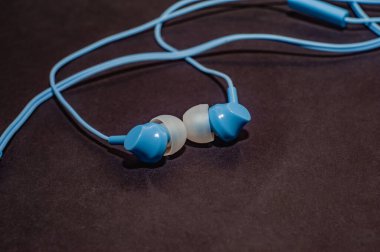 Tek renkli siyah bir yüzeye yakın plan mavi kablo kulaklıklar. Bir cep telefonu için kulaklık.