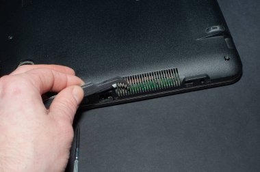 Defterin arka kapağını kaldıran bir bilgisayar tamircisinin elleri. Bilgisayar tamircisi. Mühendis dizüstü bilgisayar bakımını yapıyor. Elektronik parçaları tamir eden bir donanım geliştiricisi. Bilgisayar teknolojisi