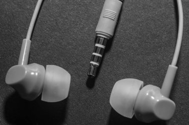 Tek renkli siyah bir yüzeye yakın plan beyaz kablo kulaklıklar. Bir cep telefonu için kulaklık. Müzik