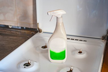 Gri masadaki tabakların yanında temizlik ürünleri ve süngerler, yazı için yer. Bulaşık malzemeleri..