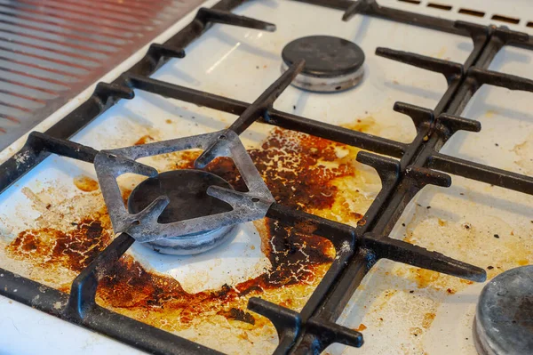 Dirty stove with food leftovers. Unclean gas kitchen cooktop with greasy spots, old fat stains, fry spots and oil splatters.