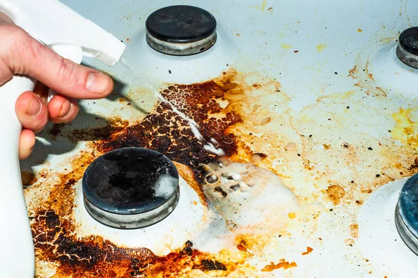 Dirty stove with food leftovers. Unclean gas kitchen cooktop with greasy spots, old fat stains, fry spots and oil splatters.