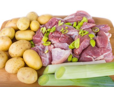 Meat pieces and potatoes on a chopping board
