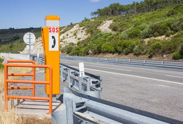 SOS sign and phone box on highway — Stock Photo, Image