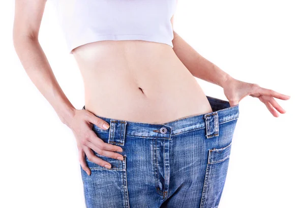 Slim woman shows her weight loss by wearing an old jeans Royalty Free Stock Images