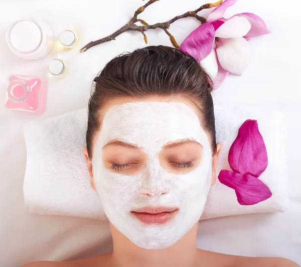 Young beautiful girl receiving pink facial mask — Stock Photo, Image