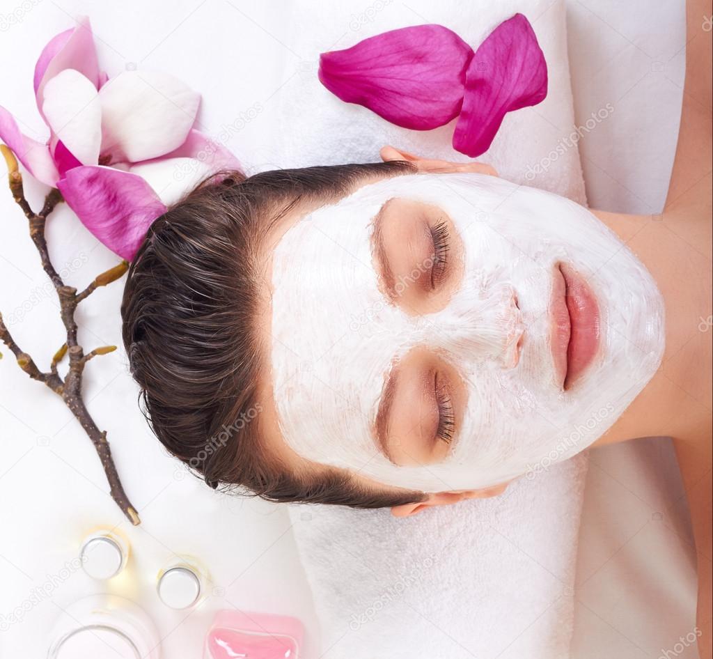 Young beautiful girl receiving pink facial mask