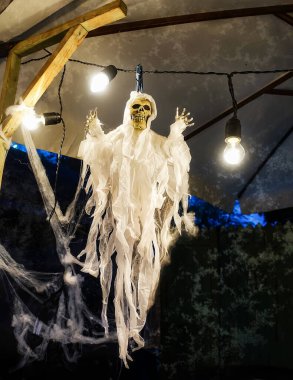 Cadılar Bayramı 'nda bir ışık çelenginin yanında örülmüş bir iskelet ve örümcek ağları asılı duruyor. Azizlerin, cadılar bayramının ve ölmüş ruhların günü için ev dekorasyonu. Ölüler Günü için dekoratif alan                               