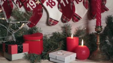 Şömine rafında kırmızı mumlar Noel oyuncakları. Çatıda Noel ağacı olan kırmızı bir araba, yeşil ladin dalları, yanan mumlar, bir Advent takvimi ve çelenk ışıkları..