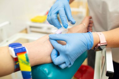 Hemşire bir şırınga tutuyor ve hastaya damar içi enjeksiyon yapıyor. Laboratuvar asistanının elinde şırınga olan koruyucu eldivenli bir iğne. Klinikteki hastalar için tıbbi prosedürler. Laboratuvarda iğne ve kan bağışı.