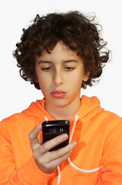 A young boy is looking at his mobile phone — Stock Photo, Image