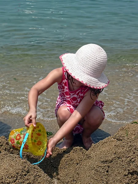 一个小女孩玩在海滩上的沙子斗 — 图库照片