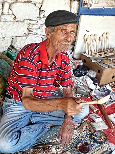 Local old man is showing a wooden spoon he made — Stock Photo, Image