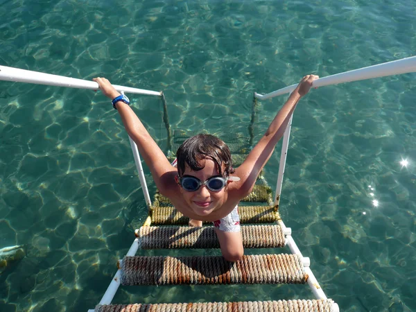 Jonge jongen beklimmen van de ladder in zee — Stockfoto