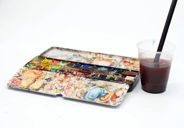 Caixa aquarela com um pincel em um copo — Fotografia de Stock