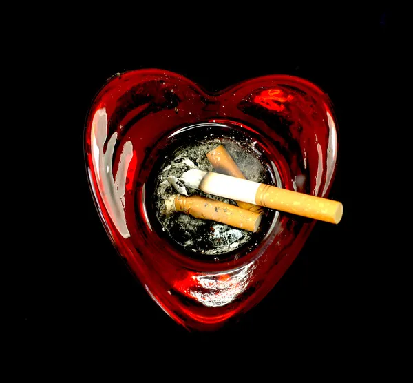 Cigarette butts in a heart shaped ashtray — Stock Photo, Image