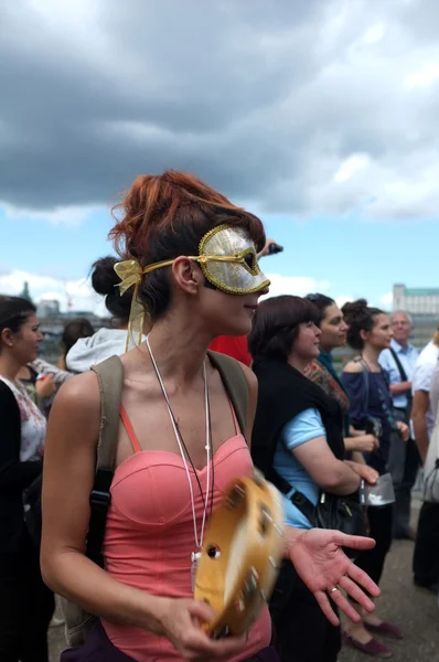 Masked female protester plays tambourine — Zdjęcie stockowe