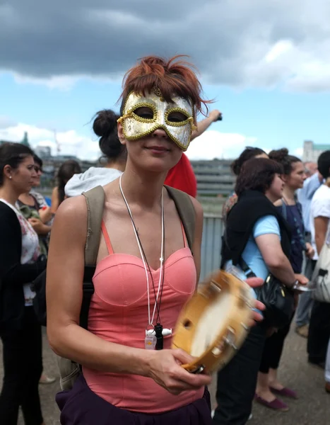 Masked female protester plays tambourine — Zdjęcie stockowe