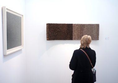 bir galeride sanat ile ilgilenen ziyaretçi