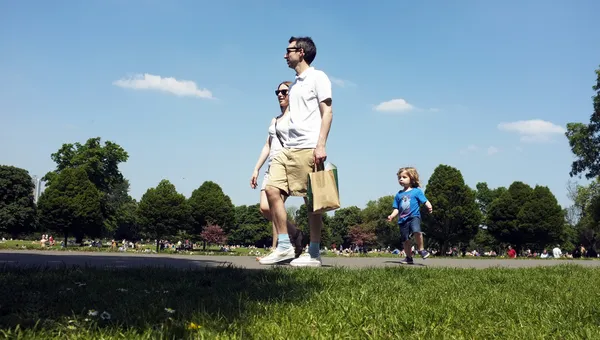 Οικογένεια περπάτημα σε ένα πάρκο με το γαλάζιο του ουρανού — Φωτογραφία Αρχείου