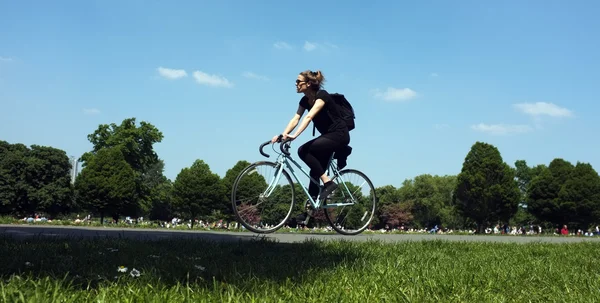 Mujer joven está en bicicleta en un parque — Foto de Stock