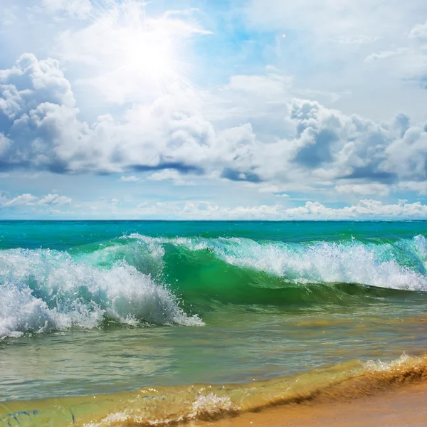 Wunderschöner tropischer Strand mit gelbem Sand, der unter hellem Sonnenlicht plätschernde lockige Wellen bricht — Stockfoto