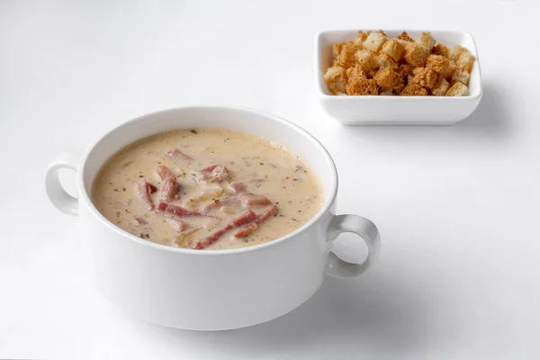 Sopa na tigela e croutons no fundo branco — Fotografia de Stock