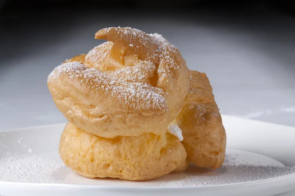 Choux gebak soezen, geïsoleerd op een plaat, naar witte achtergrond — Stockfoto