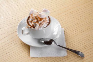 Beyaz fincan kahve kaşık, ahşap masa ile üst krema ve karamel sos ile