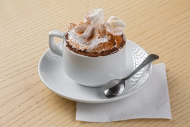 Beyaz fincan kahve kaşık, ahşap masa ile üst krema ve karamel sos ile