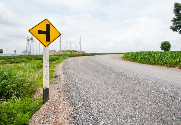 T junction road signpost beside a curve road against cloudy sky — Stock Photo, Image