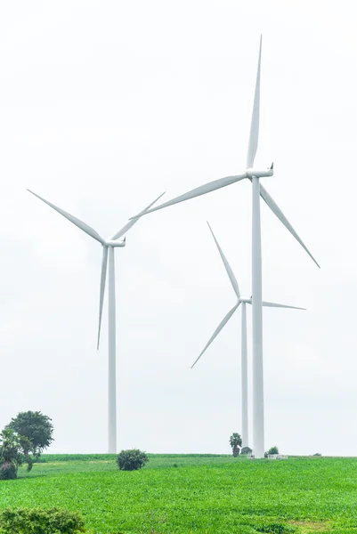 Energiebesparende, windturbines tegen zwaar bewolkt op groen veld — Stockfoto