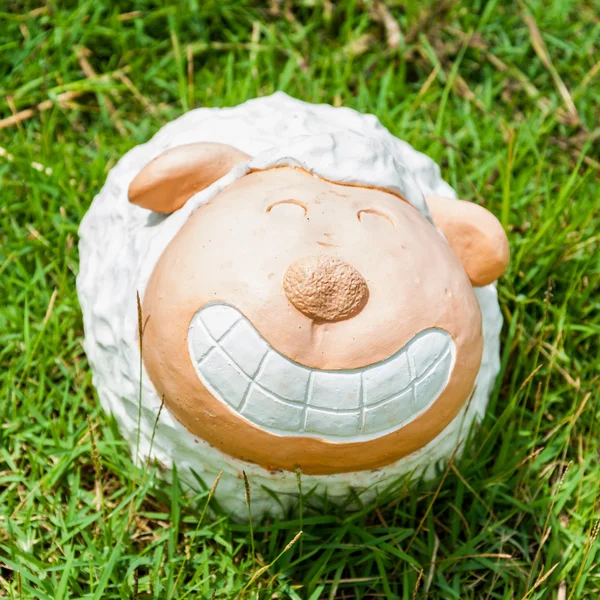 Smile white sheep statue in green grass on daytime — Stock Photo, Image