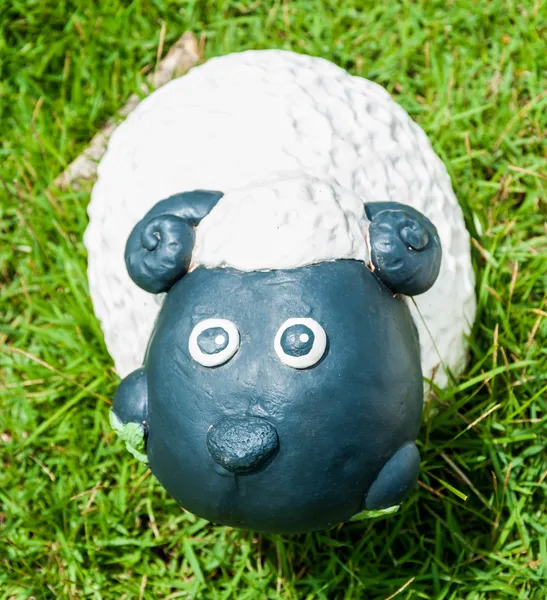 Smile white sheep statue in green grass on daytime — Stock Photo, Image