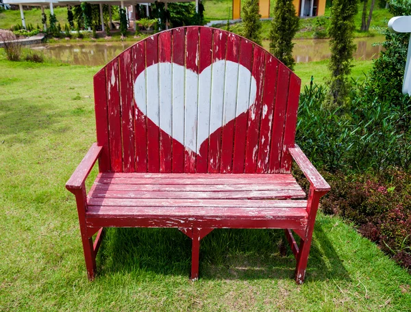 Banquette rouge avec symbole de coeur dans le jardin ou le parc — Photo