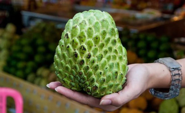 Suiker of Custardappel in hand op fruit markt achtergrond — Stockfoto