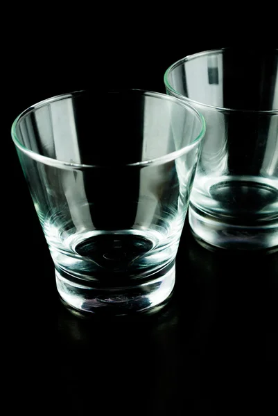 Vasos vacíos para whisky sobre una superficie reflectante sobre fondo negro — Foto de Stock