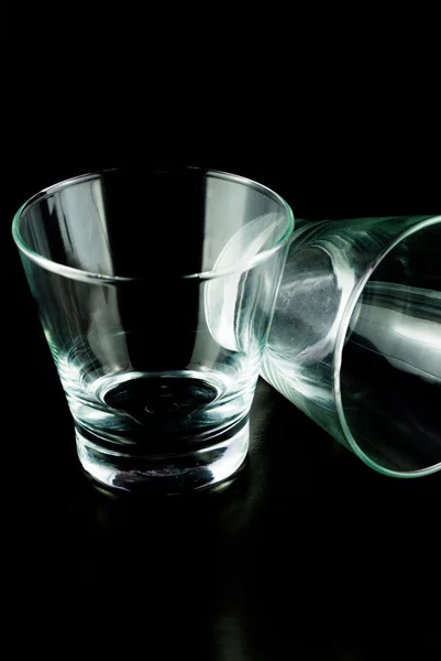 Vasos vacíos para whisky sobre una superficie reflectante sobre fondo negro — Foto de Stock