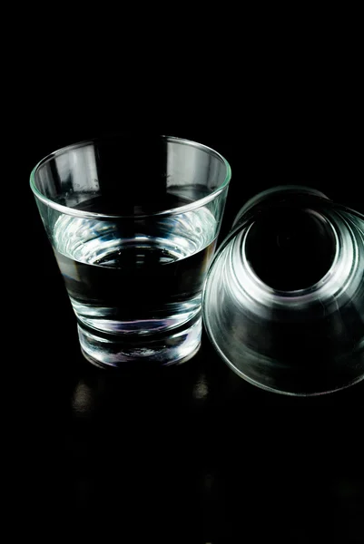 Vasos vacíos para whisky sobre una superficie reflectante sobre fondo negro — Foto de Stock