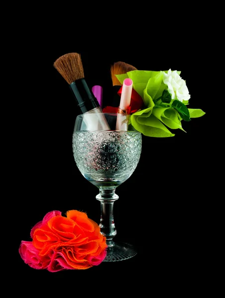 Copa de cristal de vino con cepillos y cosméticos de maquillaje aislados en negro - conjunto de cosméticos en cristal — Foto de Stock