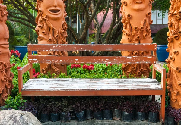 Alte Holzbank im Garten mit seltsamen Dekorationen. — Stockfoto