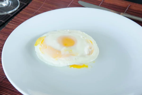 Lado soleado hasta huevo frito en plato blanco en la mesa de comedor — Foto de Stock