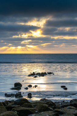Akşamları gelgitte kayalar, bulanık deniz ve bulutlarla uzun süre çekim yapar.