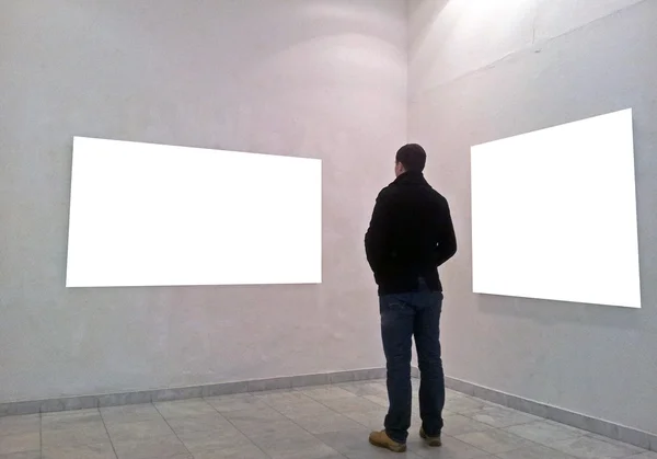 Hombre en la sala de la galería mirando marcos vacíos —  Fotos de Stock